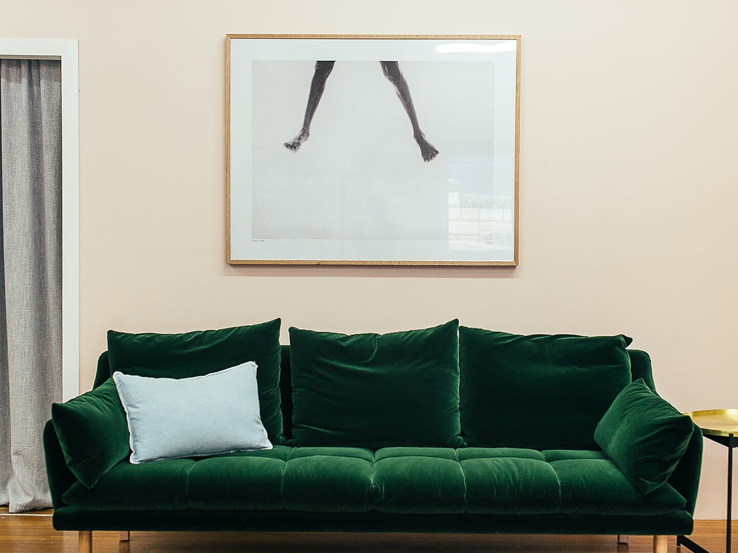 A green couch in front of a picture on the wall.