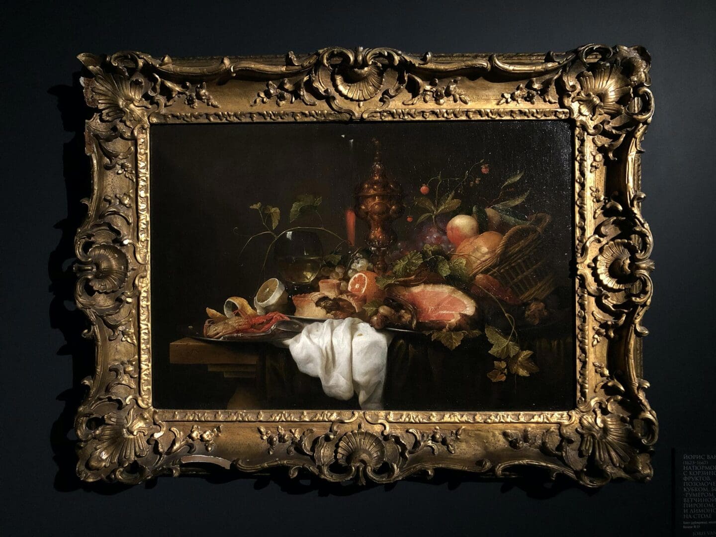 A painting of flowers and fruit in an ornate frame.