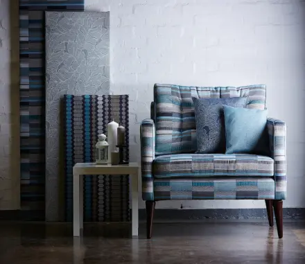 A chair with pillows and a table in the background.